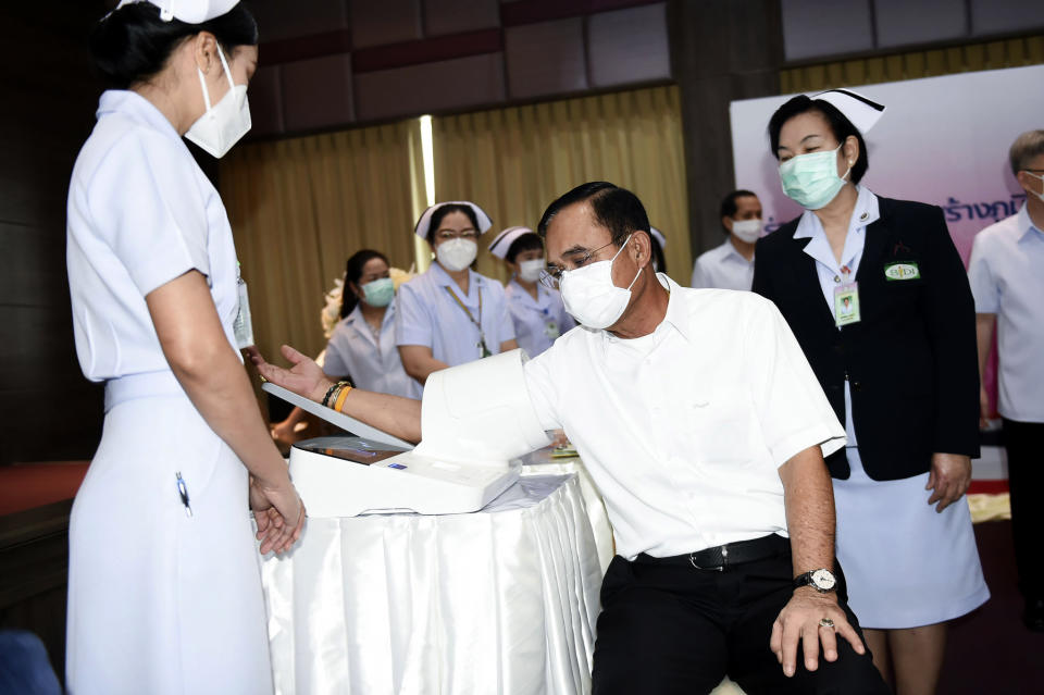 Thailand's Prime Minister Prayuth Chan-ocha, center, checks blood pressure before receiving second dose of the AstraZeneca COVID-19 vaccine at Bamrasnaradura Infectious Diseases Institute in Bangkok, Thailand, Monday, May 24, 2021. (Government Spokesman Office via AP)