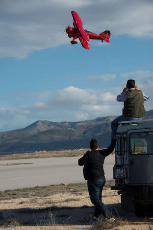 Support crew personnel watch a modern biplane representing Germany fly during the start of the Vintage Air Rally over the airport of Sitia on the island of Crete, Greece, November 11, 2016. Vintage Air Rally/Beatrice de Smet/Handout via REUTERS