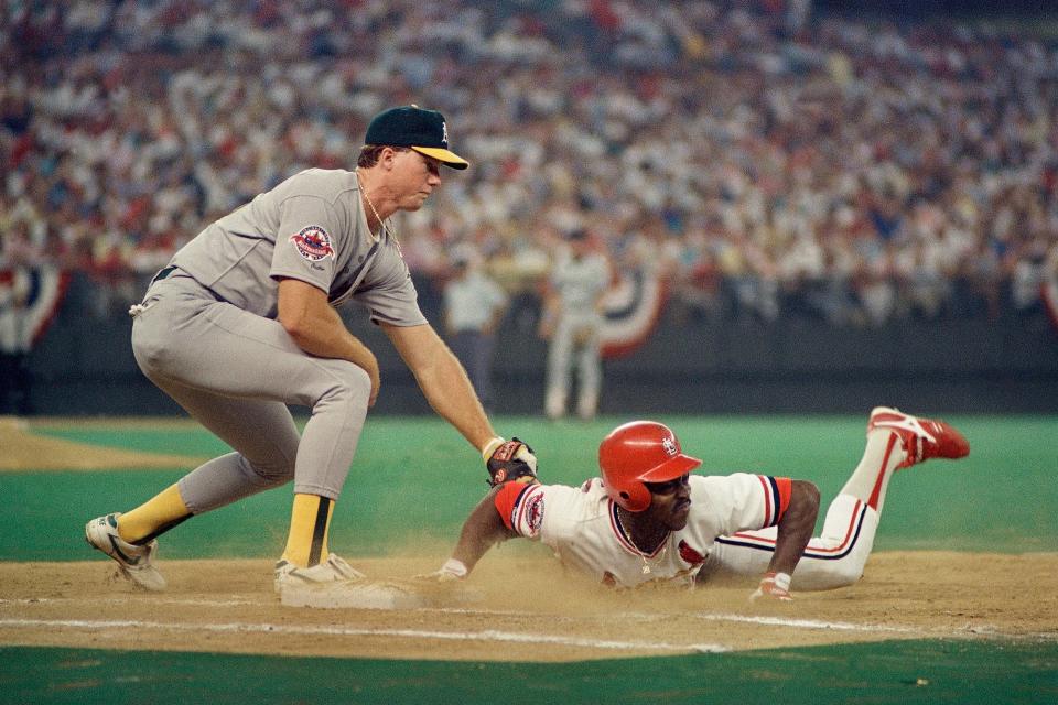 St. Louis Cardinals runner Vince Coleman dives back to first base ahead of the tag attempt by Oakland A's first baseman Mark McGwire in the 1988 All-Star Game at Riverfront Stadium in Cincinnati.