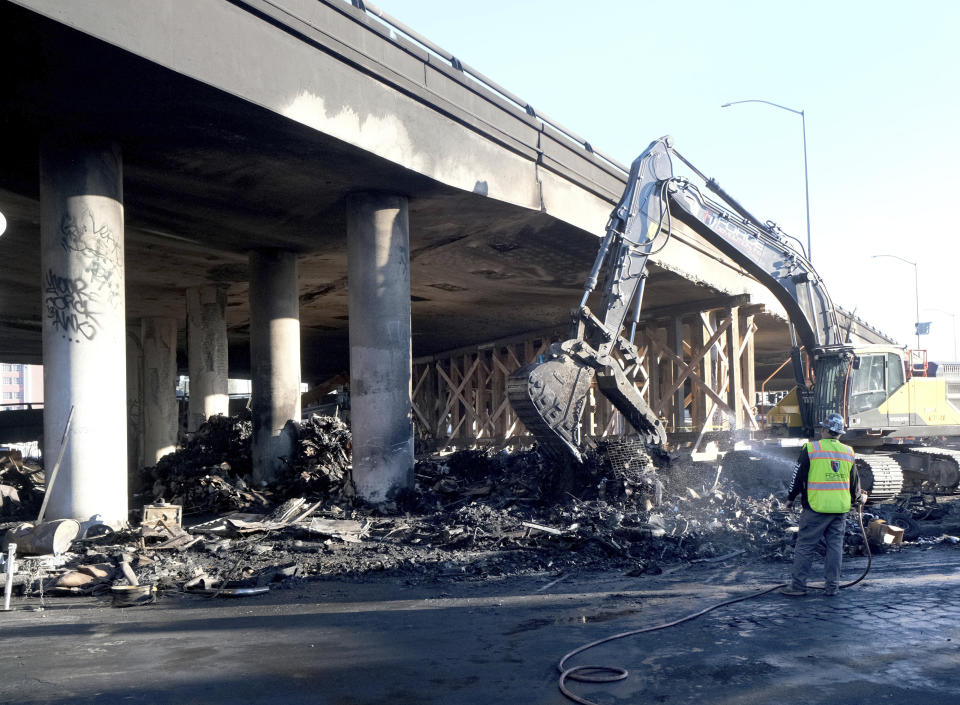 Crews continue to clear debris and shore up a stretch of Interstate 10, Tuesday morning Nov. 14, 2023, in Los Angeles. It will take at least three weeks to repair the Los Angeles freeway damaged in an arson fire, the California Gov. Gavin Newsom said Tuesday, leaving the city already accustomed to soul-crushing traffic without part of a vital artery that serves hundreds of thousands of people daily. (Dean Musgrove/The Orange County Register via AP)