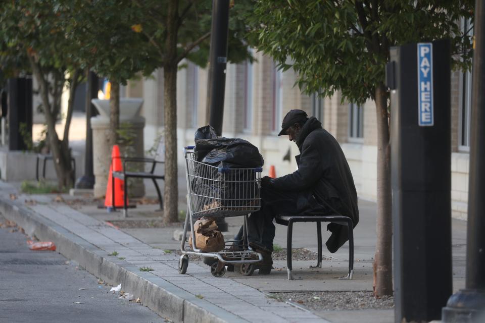 A man who appears to be homeless sits on a bench across from Parcel 5 next to Windstream and Democrat and Chronicle building.