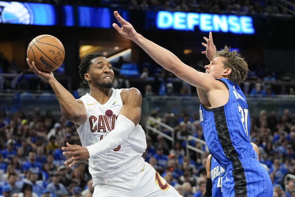 El armador de los Cavaliers de Cleveland Donovan Mitchell (izquierda) pasa el balón ante el pívot del Magic de Orlando Moritz Wagner durante la primera mitad del Juego 4 de la serie de primera ronda de playoffs de la NBA, el sábado 27 de abril de 2024, en Orlando, Florida. (AP Foto/John Raoux)