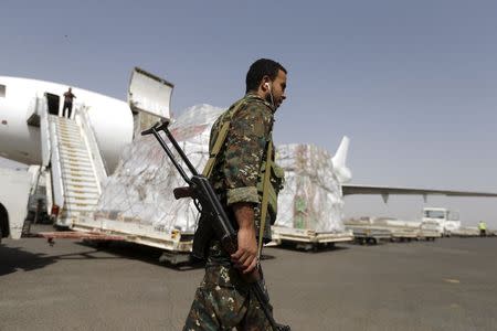 A Houthi militant walks past a shipment of emergency medical aid for the Red Cross being unloaded from a plane at Sanaa airport April 11, 2015. REUTERS/Khaled Abdullah