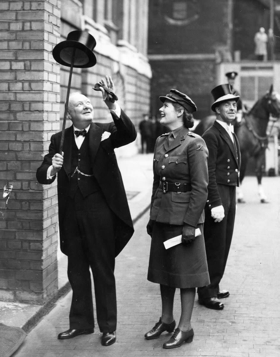 Winston Churchill shows off his party trick, balancing a top hat on his walking stick as his amused daughter Mary watches on outside the Mansion House in London on June 30, 1943.