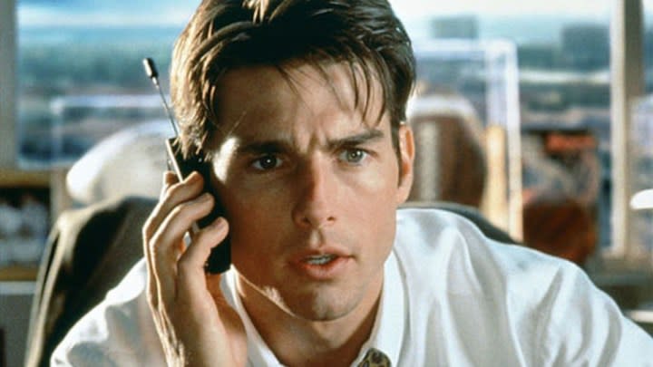 Tom Cruise sits a desk on the phone.