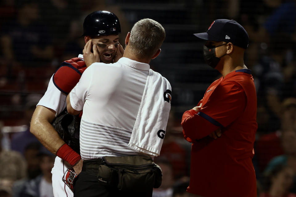 Boston Red Sox catcher Kevin Plawecki is checked by a trainer as manager Alex Cora looks on after being injured during the fourth inning of a baseball game against the Houston Astros Tuesday, June 8, 2021, at Fenway Park in Boston. Plawecki left the game. (AP Photo/Winslow Townson)