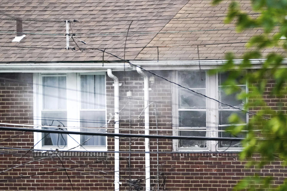 Smoke can be seen coming from broken windows in homes near the 4800 block of Broad Street in the Garfield neighborhood of Pittsburgh on Wednesday, Aug. 23, 2023. A person facing eviction opened fire from inside a Pittsburgh home Wednesday and was later pronounced dead after a siege that lasted much of the day, authorities said. (Benjamin B. Braun/Pittsburgh Post-Gazette via AP)