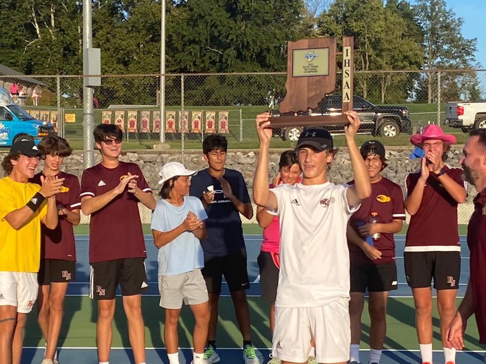 Bloomington North sophomore Connor O'Guinn lifts the boys' tennis sectional championship trophy after his win at No. 3 singles clinched the title for the Cougars on Friday.