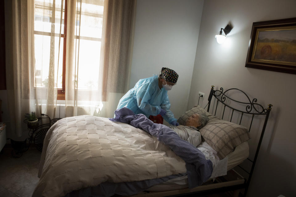 Nurse Pilar Rodríguez administers the COVID-19 vaccine to her patient Margarita Serra Crespi, 93, at her home in the town of Sa Pobla on the Spanish Balearic Island of Mallorca, Spain, Friday, April 30, 2021. Margarita who suffers from senile dementia and has been bedridden for more than two years, receives regular visits from her caregiver and nurse Pilar, one of three nurses in the town of Sa Pobla in the interior of the island and in nearby villages.(AP Photo/Francisco Ubilla)