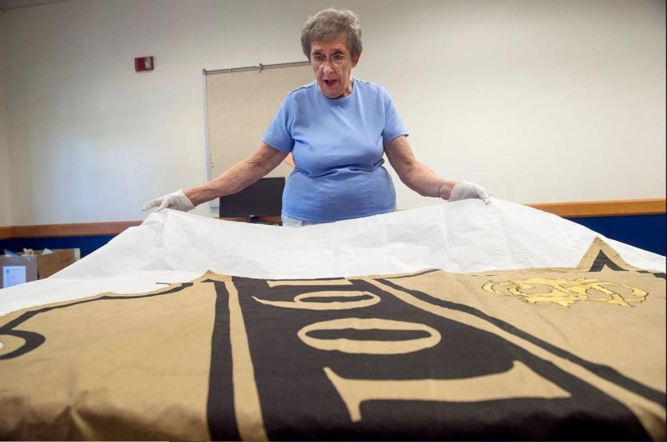 This file photo from 2016 shows Joan Bowen as she displays a class pendant from 1901 that was used during Pendant Day, a precursor to today's Color Day. This photograph was taken shortly before the archives were moved from a storage closet at the CASD Administration Building to a two-room space in the District Annex, 721 S. Sixth St.