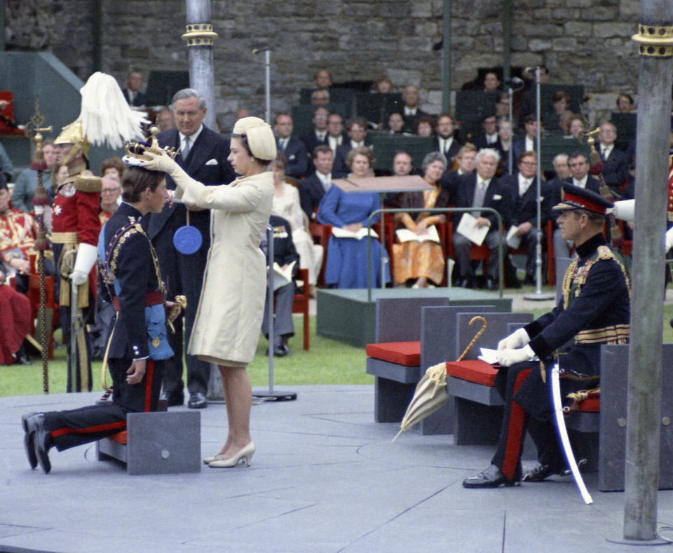 FILE - Queen Elizabeth II crowns her son Charles, Prince of Wales during his investiture ceremony on July 1, 1969 at Caernafon Castle in Wales. Prince Philip the Duke of Edinburgh is seated at right. After waiting 74 years to become king, Charles has used his first six months on the throne to meet faith leaders across the country, reshuffle royal residences and stage his first overseas state visit. With the coronation just weeks away, Charles and the Buckingham Palace machine are working at top speed to show the new king at work. (AP Photo, File)