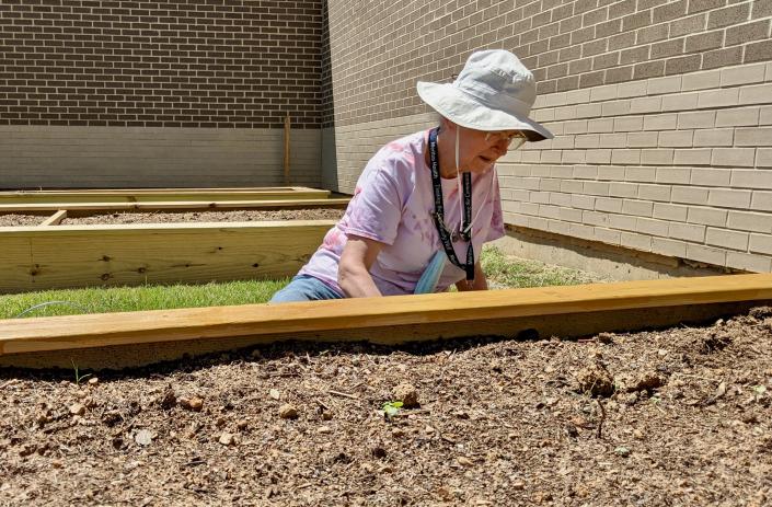 Mary Sue Cochran, a retired Meritus Medical Center nurse and now a volunteer at the hospital, applies preservative to a wooden garden bed at the new Healthy Meritus Garden.