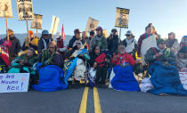Demonstrators gather to block a road at the base of Hawaii's tallest mountain, Monday, July 15, 2019, in Mauna Kea, Hawaii, to protest the construction of a giant telescope on land that some Native Hawaiians consider sacred. (AP Photo/Caleb Jones)