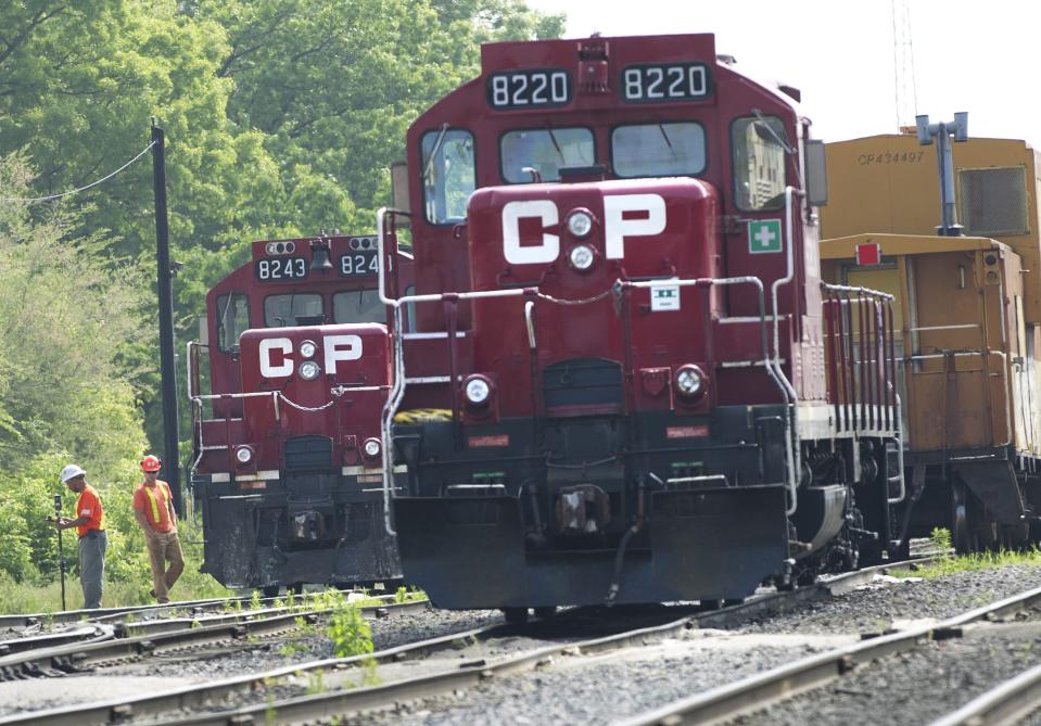 FILE - In this May 23, 2012, file photo, surveyors work next to Canadian Pacific Rail trains parked on the tracks in Toronto. As deal talks begin, Canadian National railroad says on Monday, April 26, 2021 it is receiving broad support for its $33.7 billion bid to buy Kansas City Southern. (Nathan Denette/The Canadian Press via AP, File)