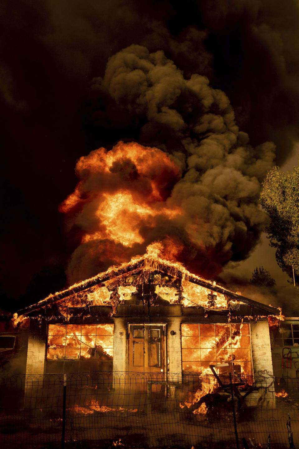 Flames consume a home as the Sugar Fire, part of the Beckwourth Complex Fire, tears through Doyle, Calif., Saturday, July 10, 2021. Pushed by heavy winds amid a heat wave, the fire came out of the hills and destroyed multiple residences in central Doyle. (AP Photo/Noah Berger)