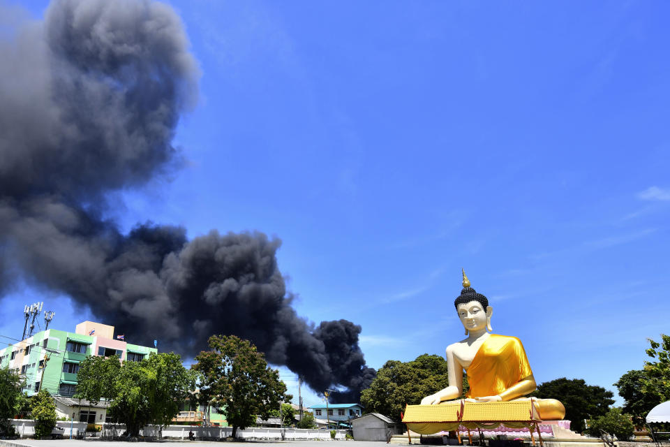 Rising smoke is seen behind the giant Buddha statue in Samut Prakan province, Thailand, Monday, July 5, 2021. A massive explosion at a factory on the outskirts of Bangkok early Monday shook an airport terminal serving Thailand's capital and prompted the evacuation of residents from the area. (AP Photo)