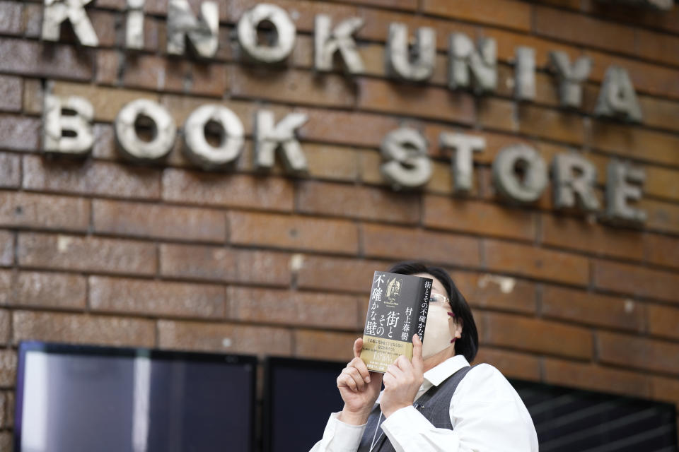 A shop clerk advertises a Japanese writer Haruki Murakami's new novel "The City and Its Uncertain Walls" on the first day for sale at Kinokuniya bookstore in Shinjuku district on early Thursday, April 13, 2023, in Tokyo. Murakami wrote a story of a walled city when he was fresh off his debut. More than four decades later, as a seasoned and acclaimed novelist, he gave it a new life as “The City and Its Uncertain Walls.”(AP Photo/Eugene Hoshiko)