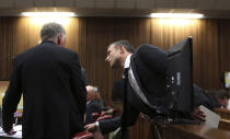 Oscar Pistorius, right, speaks to an unidentified member of his legal team whilst standing in the dock during his trial at the high court in Pretoria, South Africa, Monday, March 3, 2014. Pistorius is charged with murder with premeditation in the shooting death of girlfriend Reeva Steenkamp in the pre-dawn hours of Valentine's Day 2013. (AP Photo/Themba Hadebe, Pool)