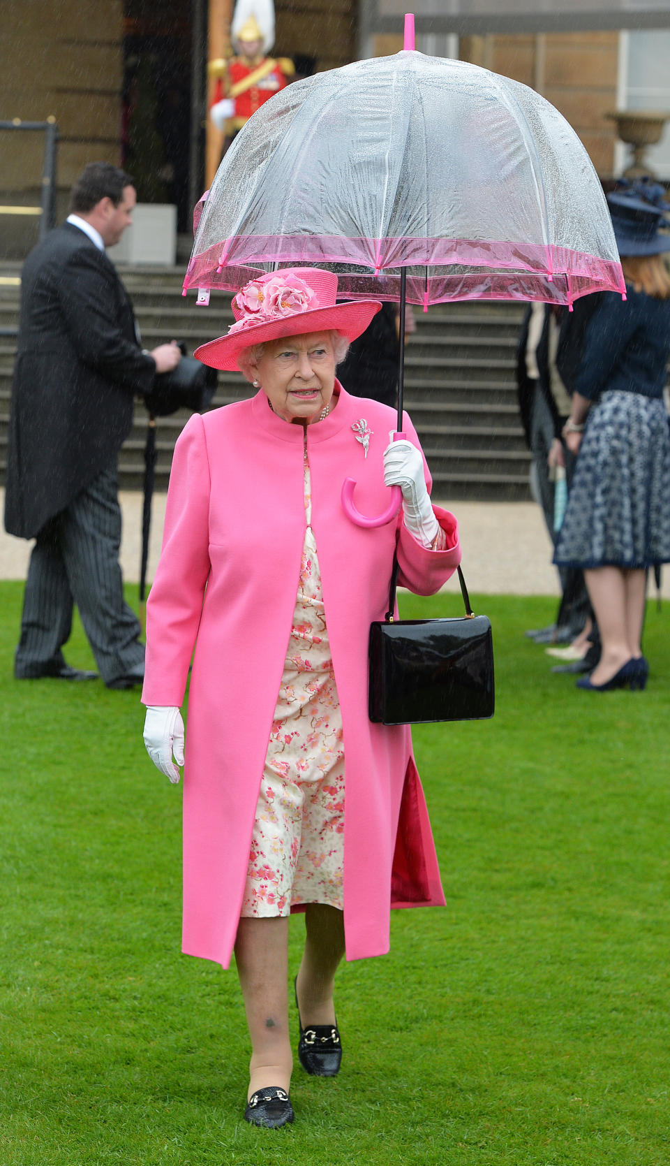 Britain's Queen Elizabeth II walks under an umbrella in the garden of Buckingham Palace in London as up to 8,000 guests attend the first royal garden party of the year on May 10, 2016.  / AFP / POOL / John Stillwell        (Photo credit should read JOHN STILLWELL/AFP/Getty Images)