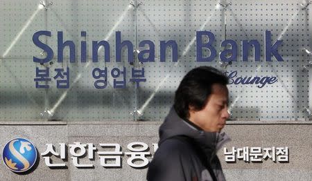 A man walks past the headquarters of Shinhan Bank in Seoul February 4, 2010. REUTERS/Jo Yong-Hak