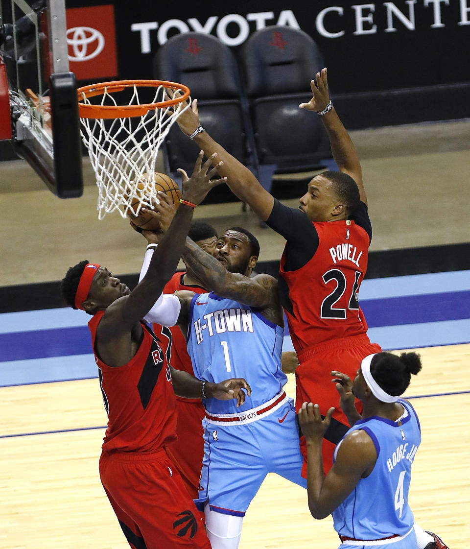 Houston Rockets' John Wall (1) drives to basket between Toronto Raptors' Pascal Siakam (43) and Norman Powell (24) during the third quarter of an NBA basketball game Monday, March 22, 2021, in Houston. (Bob Levey/Pool Photo via AP)