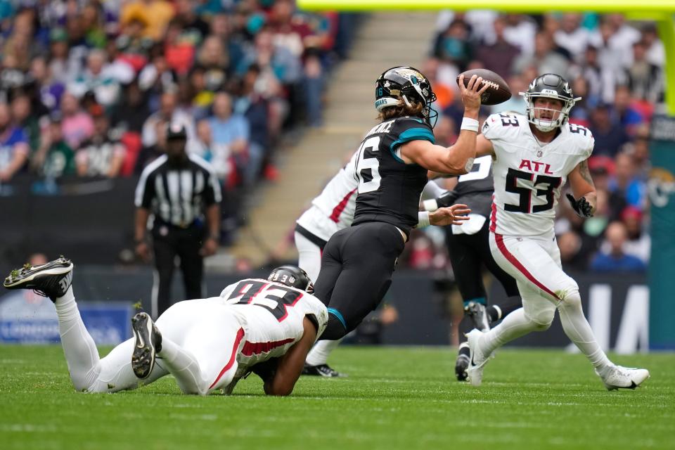 Jacksonville Jaguars quarterback Trevor Lawrence (16) passes the ball as he is tackled by Atlanta Falcons defensive tackle Calais Campbell (93) during an NFL football game between the Atlanta Falcons and the Jacksonville Jaguars at Wembley stadium in London, Sunday, Oct. 1, 2023. (AP Photo/Kirsty Wigglesworth)