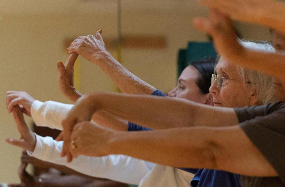 Pat Hobbs, center, stretches her arms with other patients during a yoga class for breast cancer patients on Wednesday, Oct. 4, 2023, at Memorial Rehabilitation Institute Outpatient Treatment Center in Hollywood. Yoga helps patients deal with stress, anxiety and depression by slowing down and being mindful. Alie Skowronski/askowronski@miamiherald.com