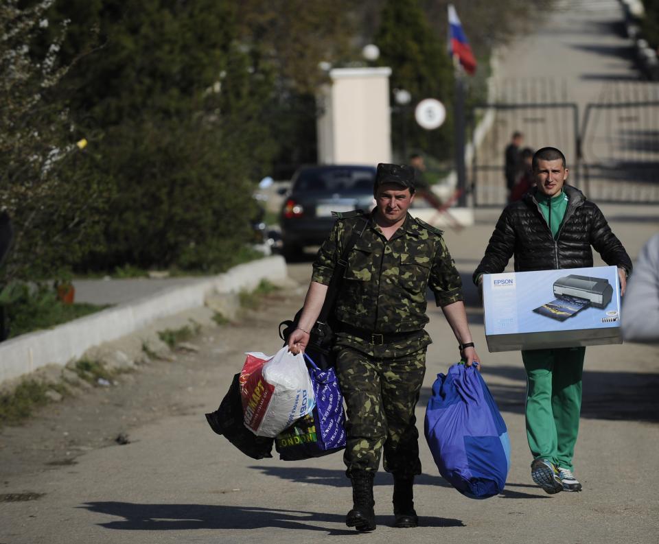 Ukrainian servicemen carry their belongings as they leave the Belbek airbase near Sevastopol, Crimea, Friday, March 28, 2014. Ukraine started withdrawing its troops and weapons from Crimea, now controlled by Russia. Russia's president says Ukraine could regain some arms and equipment of military units in Crimea that did not switch their loyalty to Russia. (AP Photo/Andrew Lubimov)