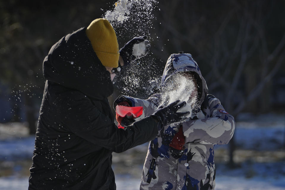 A woman plays snow fight with a child on a snow covered compound near a residential building in Beijing, Sunday, Dec. 17, 2023. Days of snowfall is followed by bitter cold. Temperatures plunged across northern China, with a cold front moving eastward from Xinjiang in the west and reaching Beijing by the weekend. (AP Photo/Andy Wong)