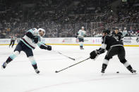 Seattle Kraken center Matty Beniers, left, shoots the puck as Los Angeles Kings defenseman Andreas Englund defends during the first period of an NHL hockey game Wednesday, April 3, 2024, in Los Angeles. (AP Photo/Mark J. Terrill)