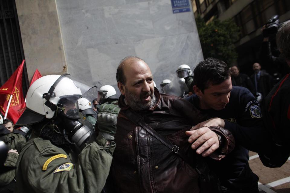 Riot policemen detain a protester during a demonstration against austerity measures in Athens, on Thursday March 6, 2014. Riot police have used tear gas and pepper spray during scuffles with union members protesting austerity measures, during a ban on demonstrations in parts of central Athens due to a visit by German President Joachim Gauck. Scuffles broke out when a group of several dozen demonstrators attempted to break through a police cordon on a major avenue in an effort to march to the Finance Ministry. (AP Photo/Kostas Tsironis)