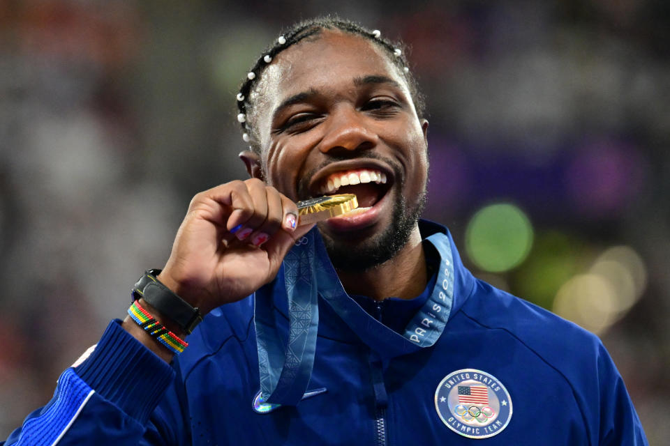 TOPSHOT - Gold medallist US' Noah Lyles celebrates on the podium during the victory ceremony for the men's 100m athletics event during the Paris 2024 Olympic Games at Stade de France in Saint-Denis, north of Paris, on August 5, 2024. (Photo by Martin  BERNETTI / AFP) (Photo by MARTIN  BERNETTI/AFP via Getty Images)