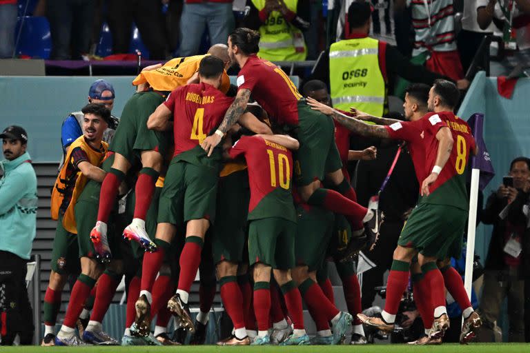 Portugal's forward #07 Cristiano Ronaldo (covered) celebrates with teammates after scoring his team's first goal from the penalty spot during the Qatar 2022 World Cup Group H football match between Portugal and Ghana at Stadium 974 in Doha on November 24, 2022. (Photo by MANAN VATSYAYANA / AFP)