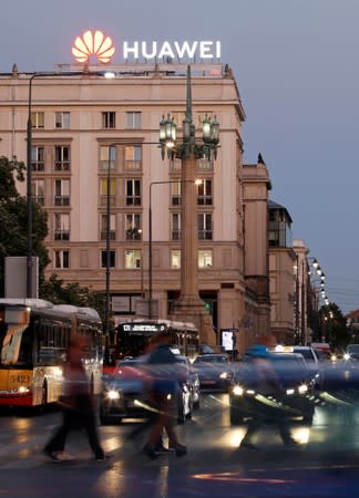 Cars pass in front of a building with Huawei's logo in the centre of Warsaw