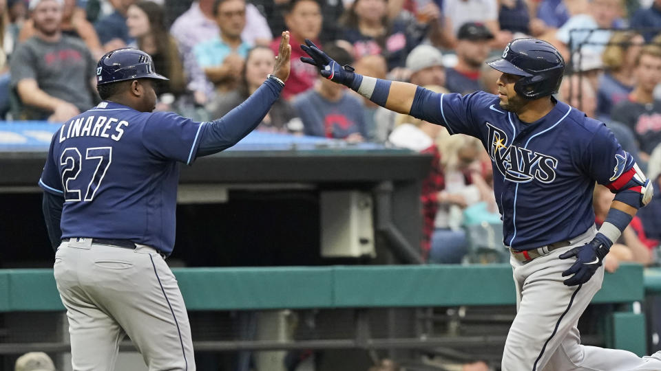 Tampa Bay Rays' Nelson Cruz, right, is congratulated by third base coach Rodney Linares after Cruz hit a solo home run during the third inning of a baseball game Friday, July 23, 2021, in Cleveland. (AP Photo/Tony Dejak)