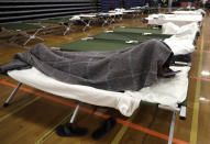 In this June 13, 2019 photo, a migrant man looks at his cellphone as he rests inside the Portland Exposition Building, in Portland, Maine. Maine's largest city has repurposed the basketball arena as an emergency shelter in anticipation of hundreds of asylum seekers who are headed to the state from the U.S. southern border. Most are arriving from Congo and Angola. (AP Photo/Elise Amendola)