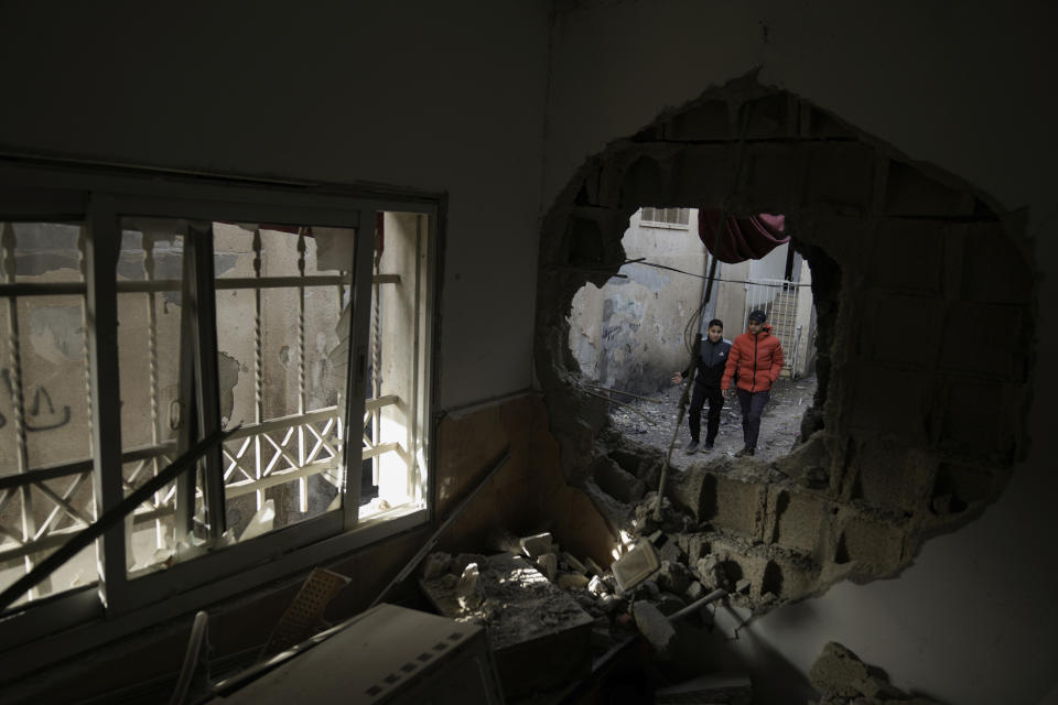 Palestinians walk by a damaged building following an Israeli army operation in Jenin refugee camp, West Bank, Sunday, Nov. 26, 2023. Israeli forces operating in the occupied West Bank killed at least eight Palestinians in a 24-hour period, Palestinian health officials said Sunday. (AP Photo/Majdi Mohammed)