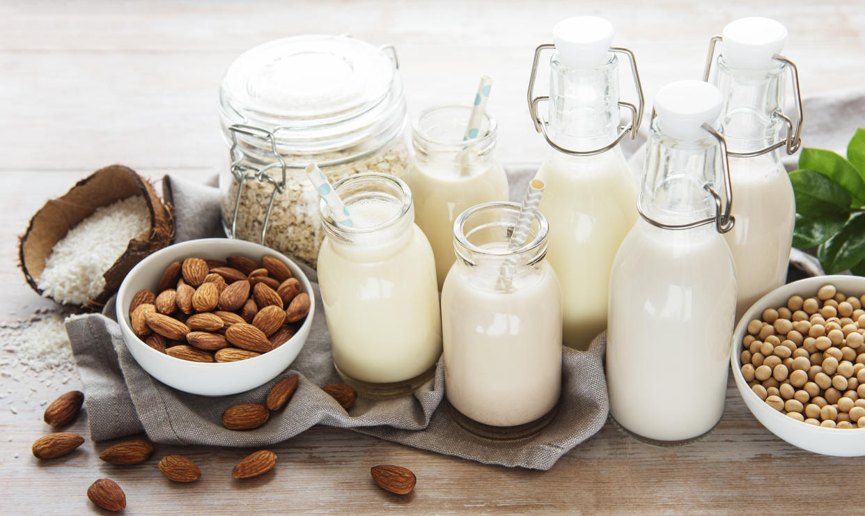Alternative types of vegan milks in glass bottles on a concrete background. Top view