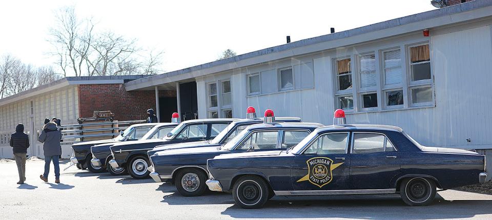 Vehicles from the 1960s are parked at the closed Foster School in Braintree for filming of "Boston Strangler" on Thursday, Jan. 27, 2022.