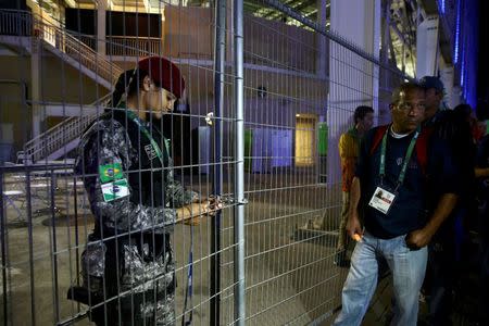 A guard locks a gate at the media entrance to the Olympics Aquatics Stadium during a security alert REUTERS/Vasily Fedosenko FOR EDITORIAL USE ONLY. NOT FOR SALE FOR MARKETING OR ADVERTISING CAMPAIGNS.