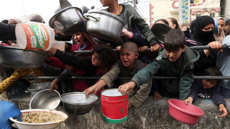 Palestinian children receive food cooked by a charity kitchen amid acute shortages in Rafah, southern Gaza, February 13, 2024. - Ibraheem Abu Mustafa/Reuters