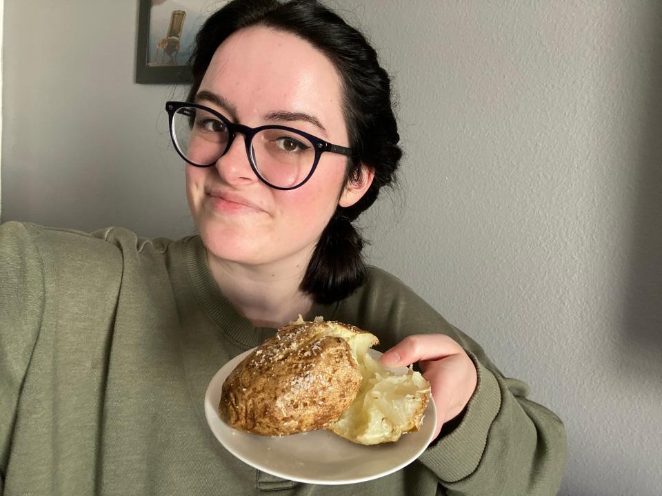 Author holding up russet baked potato on plate.