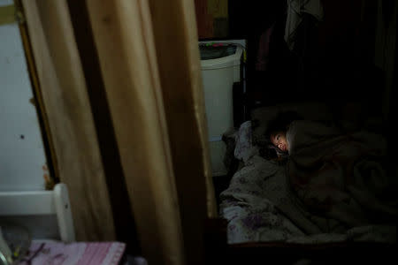 A girl looks at her mobile phone inside her flat at the abandoned Prestes Maia textile factory occupied by a homeless movement in downtown Sao Paulo, Brazil, May 13, 2018. REUTERS/Nacho Doce