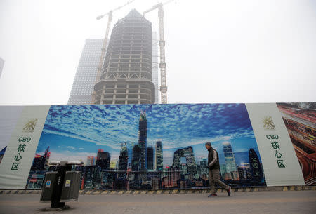 FILE PHOTO: A man walks past a building under construction in the central business district on a polluted day after a yellow alert was issued for smog, in Beijing, China November 14, 2018. REUTERS/Jason Lee /File Photo