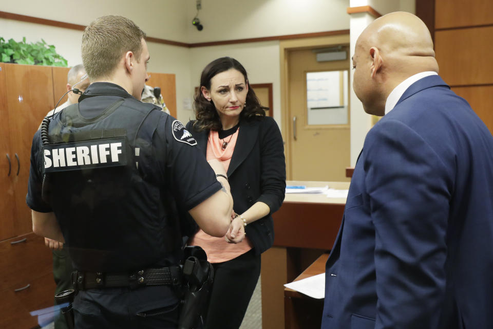 Juliette Parker, center, looks to her attorney at right as she hands over jewelry before being handcuffed by a Pierce County Sheriff's Deputy, left, Tuesday, Feb. 18, 2020, in a Pierce County courtroom in Tacoma, Wash. Parker, who is accused of posing as a baby photographer in a plot to steal a mother's baby, pleaded not guilty Tuesday to charges of assault and attempted kidnapping. The judge in the case raised her bail from $50,000 to $150,000, and she was re-booked into the Pierce County Jail. (AP Photo/Ted S. Warren)