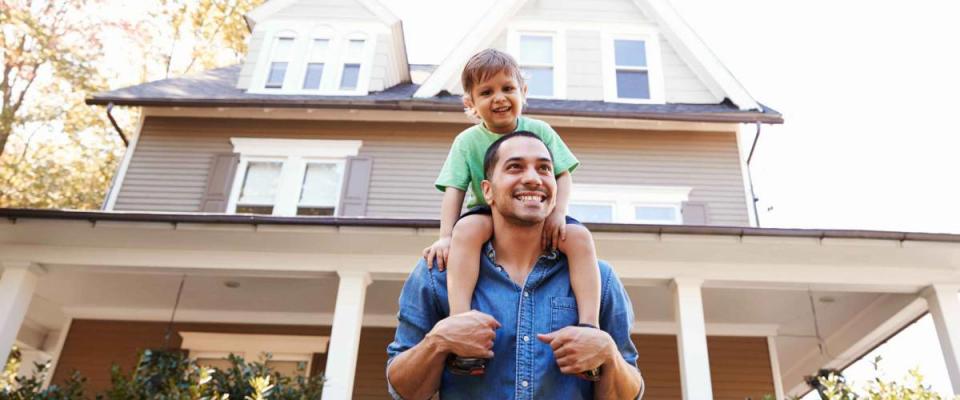 Father Giving Son Ride On Shoulders Outside House