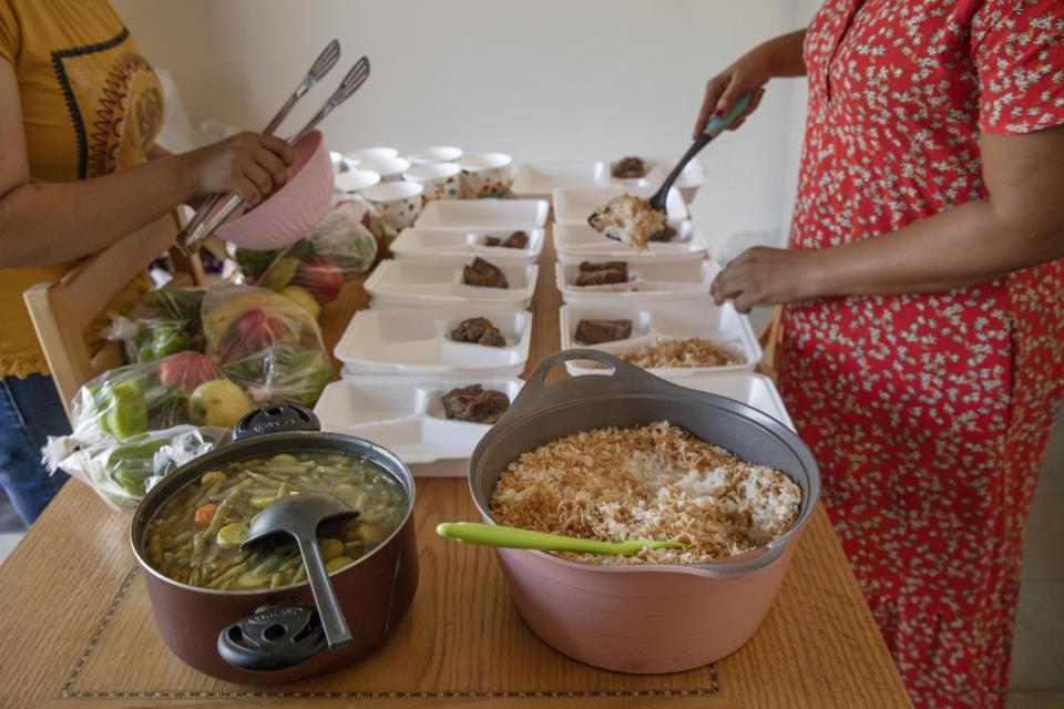 Basma Mostafa, a 30-year-old journalist who founded an initiative that sends freshly home cooked meals to quarantined coronavirus patients, right, and Fatma Youssef, a volunteer, left, package food into boxes, at an apartment, in Cairo, Egypt. Saturday, July 11, 2020. Volunteers in Egypt hope the meals will help nurse quarantined coronavirus patients back to health and provide them with some respite. In different neighborhoods in Cairo and some other cities they've enlisted people to cook, donate food or make contactless deliveries to patients' homes. (AP Photo/Nariman El-Mofty)