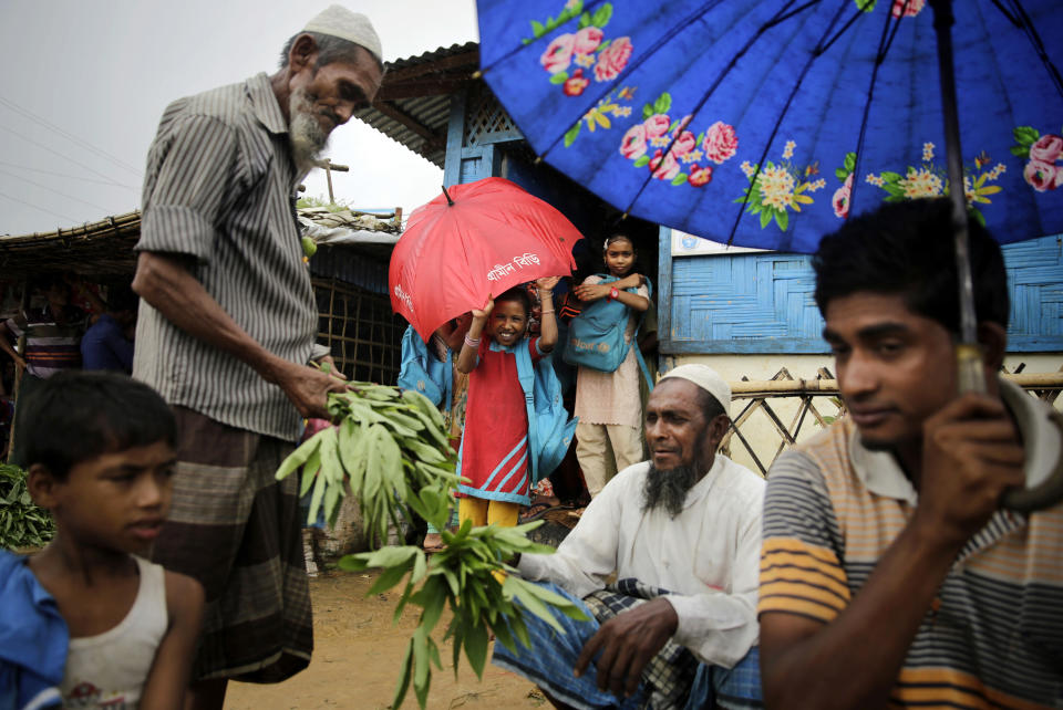 FILE - In this Aug. 28, 2018, file photo, Rohingya refugees, in the foreground, sell vegetables as girls take shelter under an umbrella as they leave a makeshift school at Kutupalong refugee camp, where they have been living amid uncertainty over their future after they fled Myanmar to escape violence a year ago, in Bangladesh. Myanmar and Bangladesh are making a second attempt to start repatriating Rohingya Muslims after more than 700,000 of them fled a security crackdown in Myanmar almost two years ago, the U.N. refugee agency said Friday, Aug. 16, 2019. (AP Photo/Altaf Qadri, File)