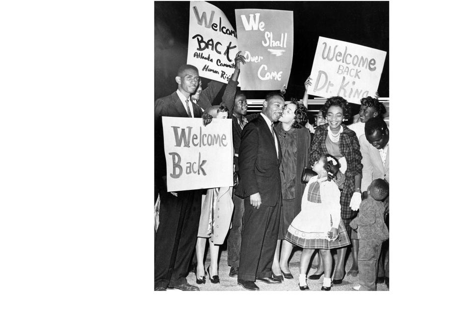 Martin Luther King Jr. is given a welcome home kiss by his wife, Coretta, upon his return to DeKalb County, Atlanta, Georgia, from the Reidsville State Prison, on Oct. 27, 1960. Pictured from left to right at the DeKalb Peachtree Airport are the Rev. Otis Moss Jr. (holding Welcome Back sign); Clark College student government vice president Ben Brown (holding We Shall Overcome sign), Martin Luther King Jr., Coretta Scott King, Christine King (with Yolanda and Martin III in foreground), DeKalb County NAACP co-founder Rosetta Williams, and Atlanta Student Movement organizer Lonnie King.