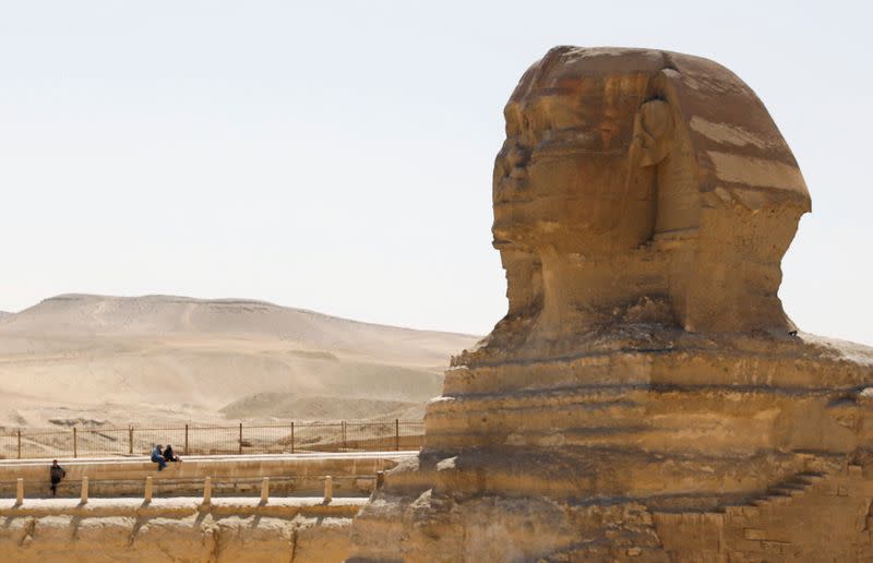 Tourists sit in front of the Sphinx at the Great Pyramids of Giza, on the outskirts of Cairo